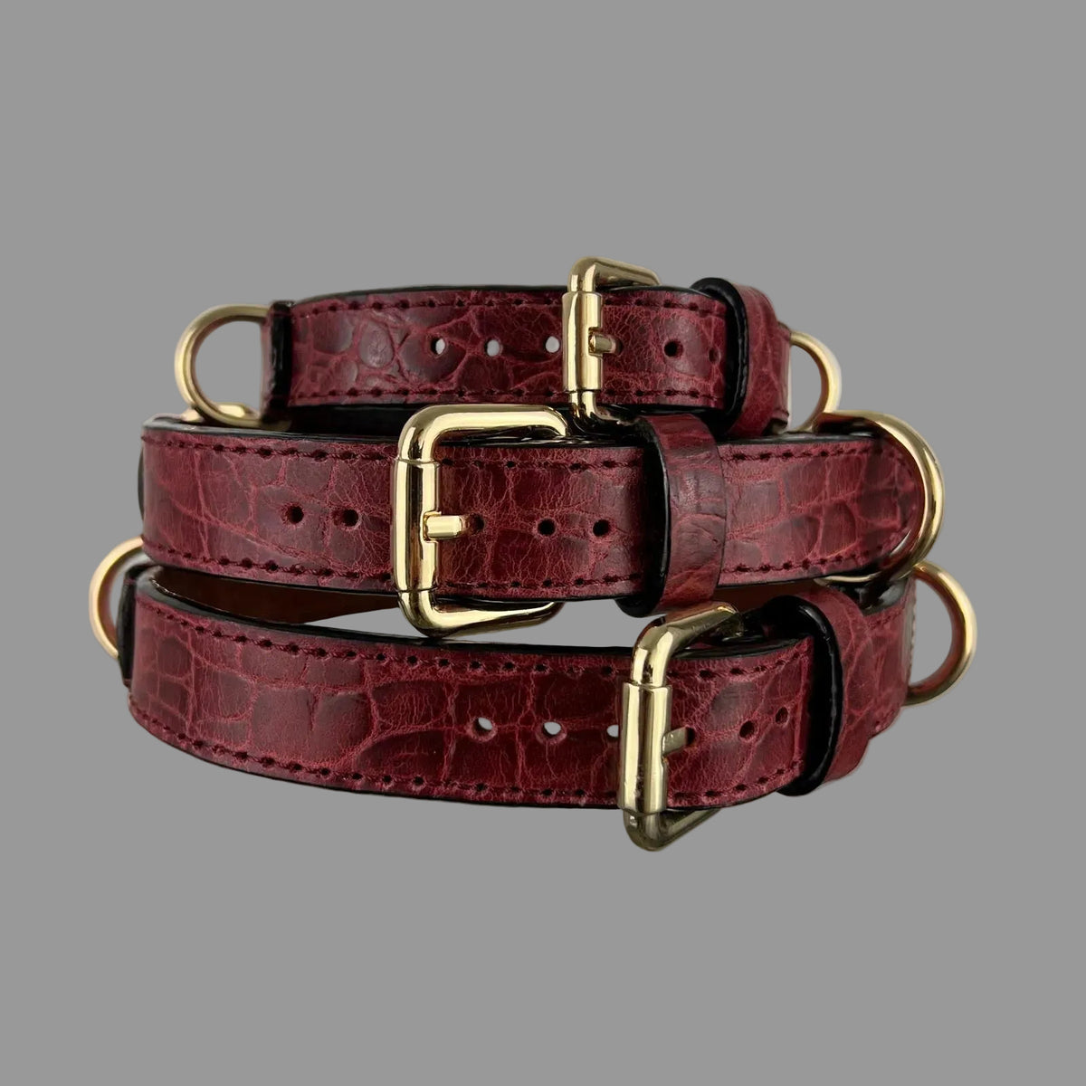 Three red crocodile-embossed leather dog collars in sizes M, L and XL with polished gold-tone hardware