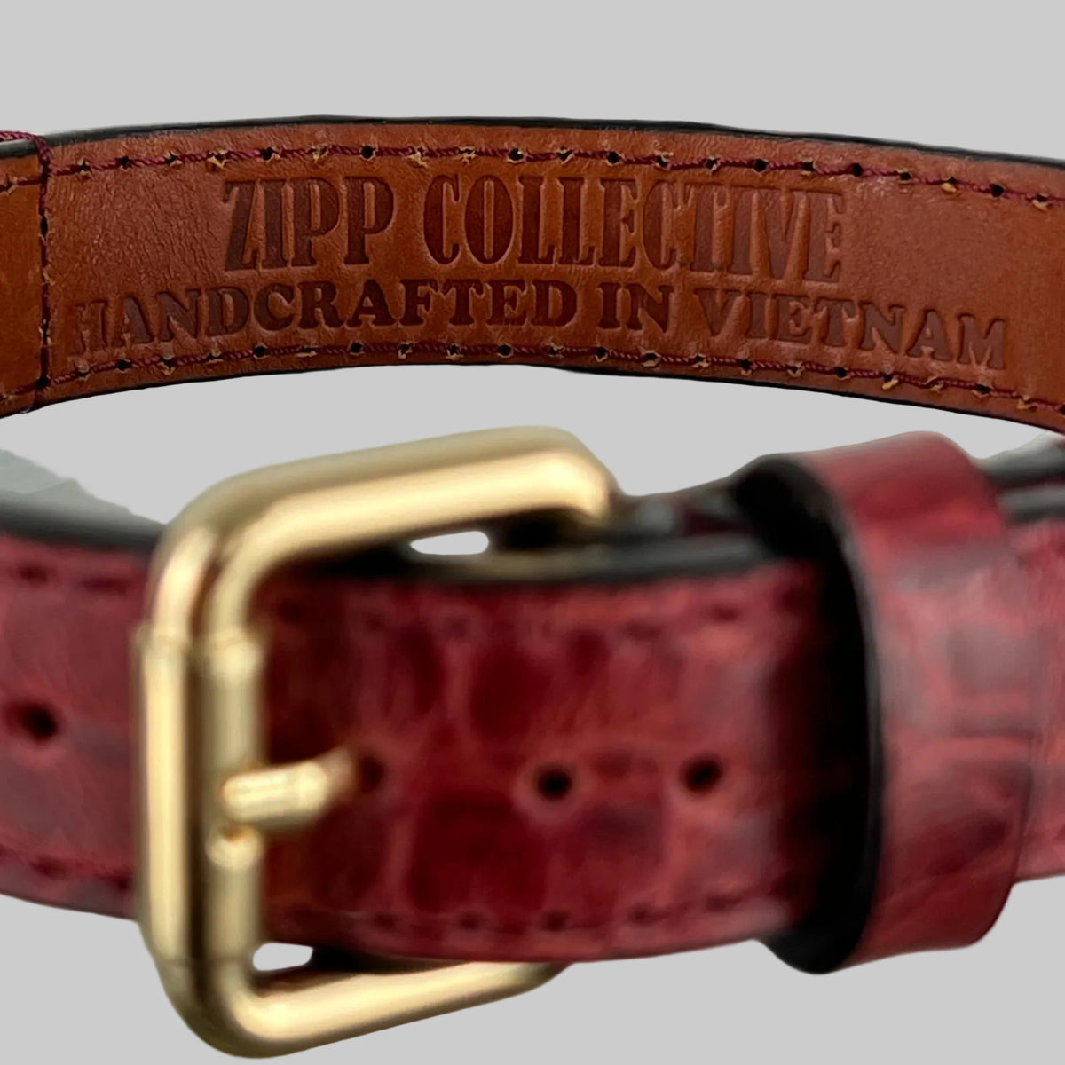 Close-up of ZIPP COLLECTIVE branding stamped inside a handcrafted red leather dog collar