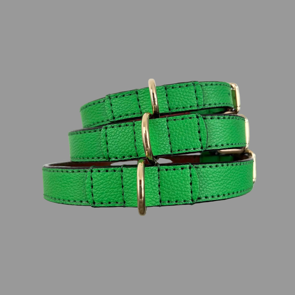 Stacked bright green leather dog collars with gold hardware
