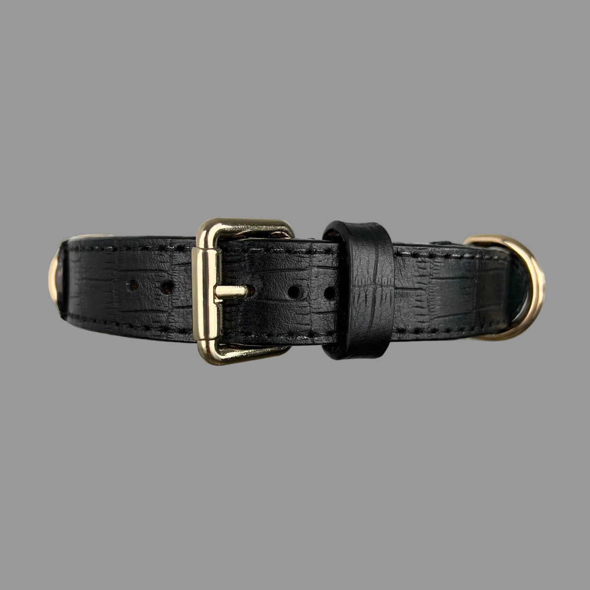 Close-up of rectangular crocodile-style embossing, black stitching and finished edges on a black leather dog collar.