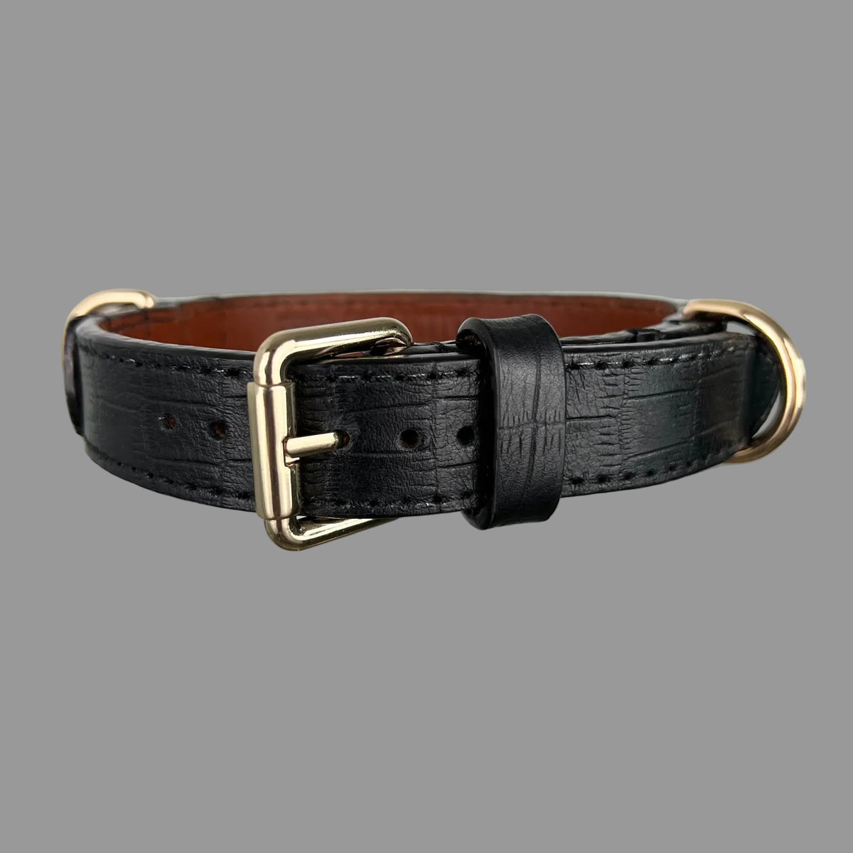 Front view of a black crocodile-embossed dog collar with a gold-tone buckle, black keeper and brown leather lining visible.