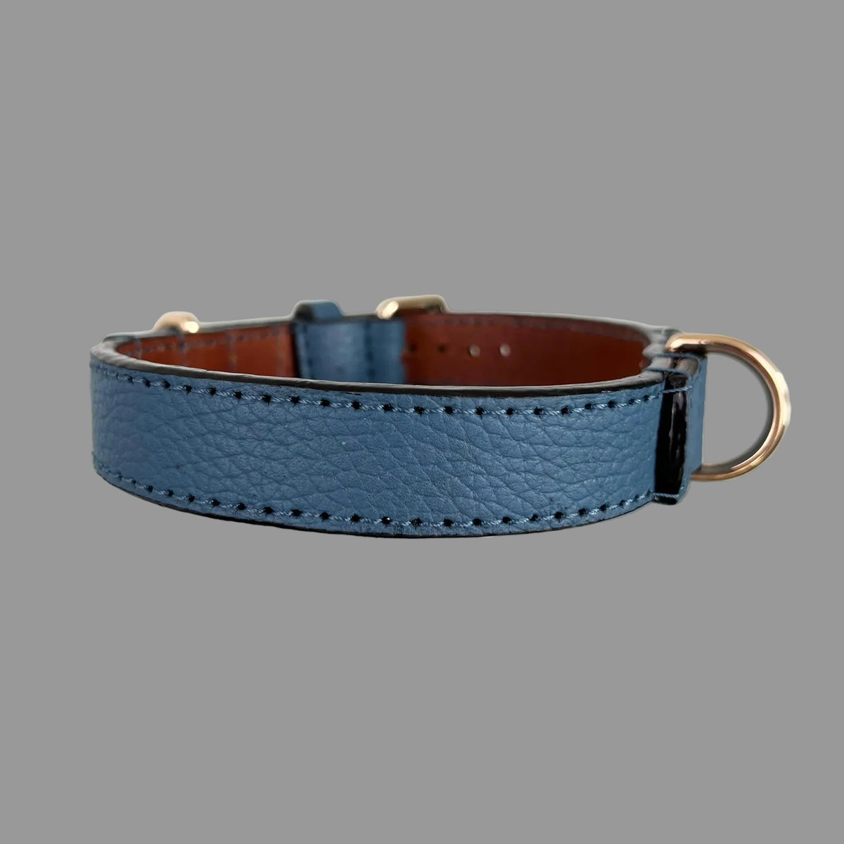 Denim-blue pebbled cowhide dog collar showing its stitched outer strap, dark edges and brown leather lining.