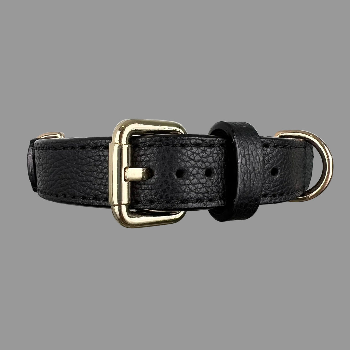 Close-up of a black pebbled leather dog collar with a gold-tone buckle, black keeper loop and adjustment holes.