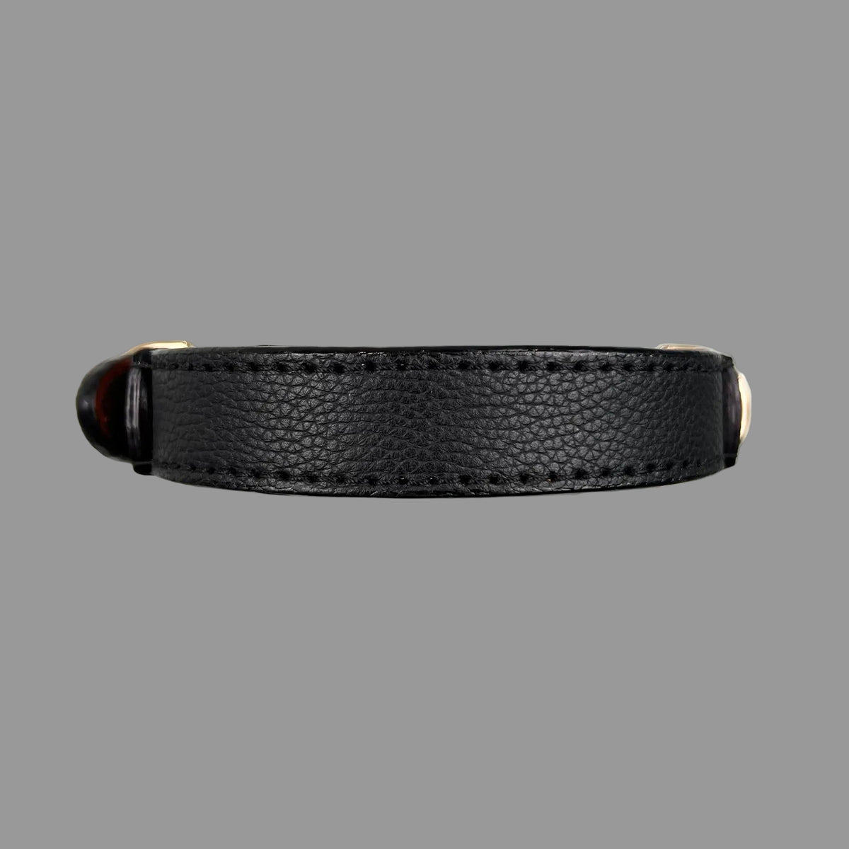 Black pebbled dog collar showing its pointed leather strap end, black keeper, gold-tone buckle and D-ring.