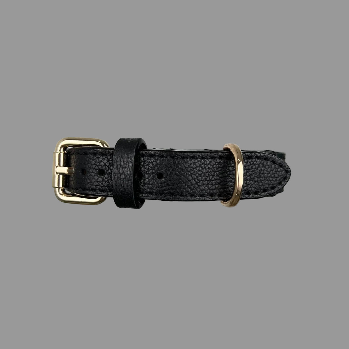 Close-up of the pebbled black cowhide surface, matching stitching and finished edges on a leather dog collar.