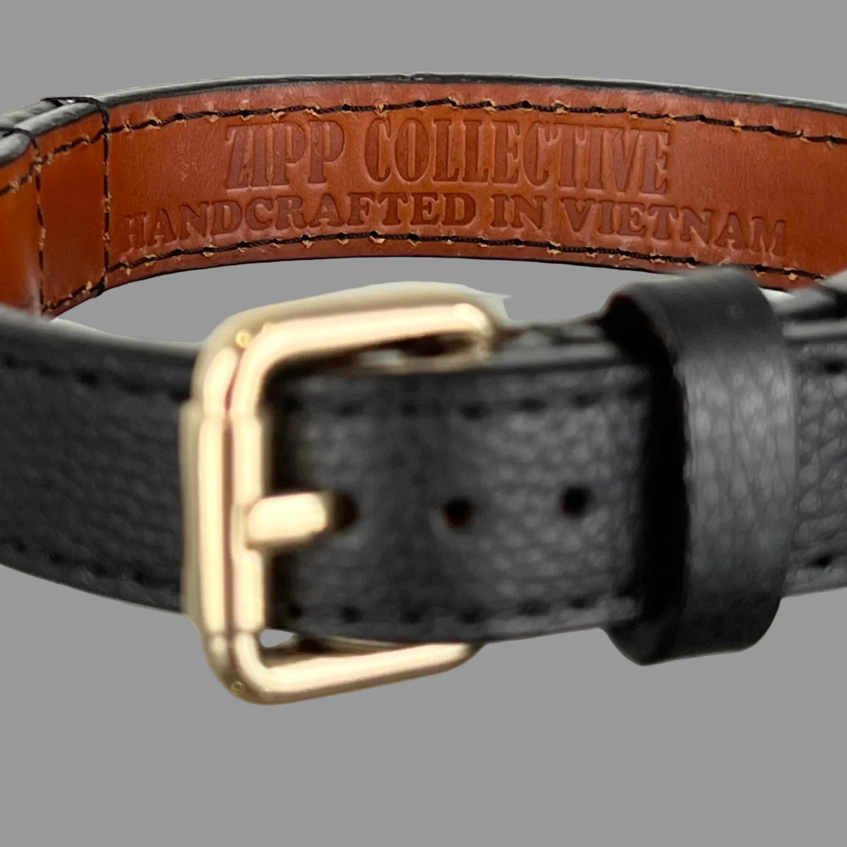 Brown leather lining stamped ZIPP COLLECTIVE — HANDCRAFTED IN VIETNAM inside a black pebbled dog collar.
