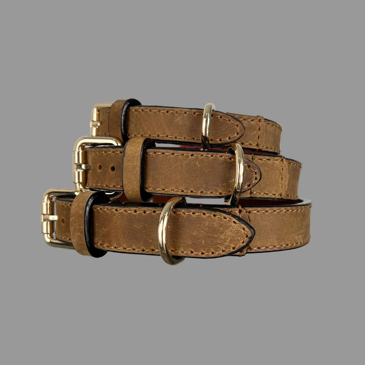 Three brown leather dog collars showing lighter tonal markings, matching stitching and contrasting dark edges.