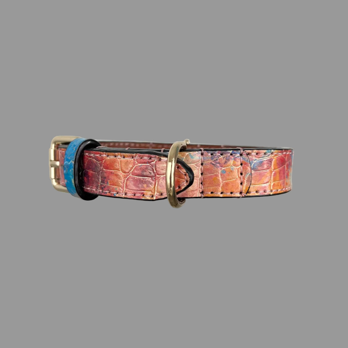 Multicolour embossed dog collar showing a gold-tone D-ring, stitched leather reinforcement and pointed strap end.