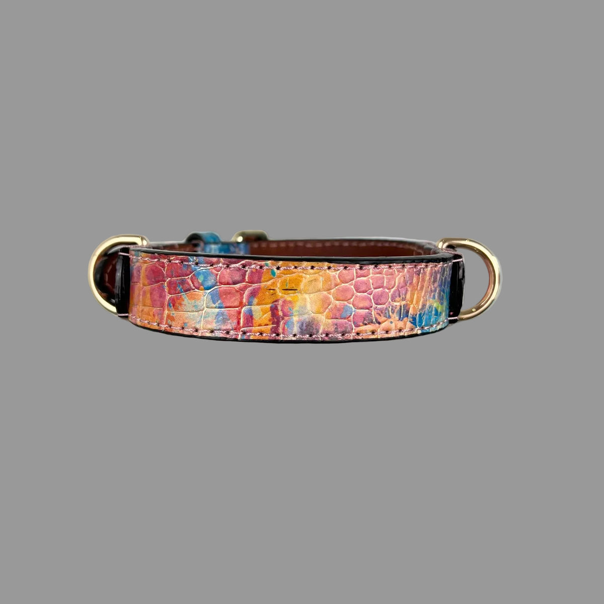 Close-up of the pink, orange, yellow and blue abstract pattern over crocodile-style embossing on a cowhide dog collar.
