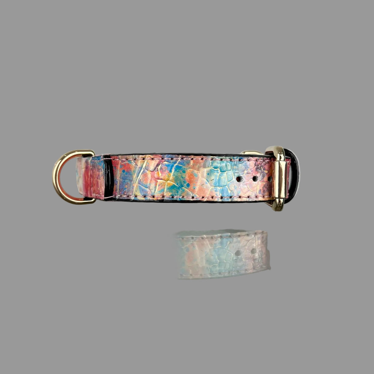 Side view of a multicolour cowhide dog collar with blue and pink croc embossing, a gold-tone D-ring and dark edges.