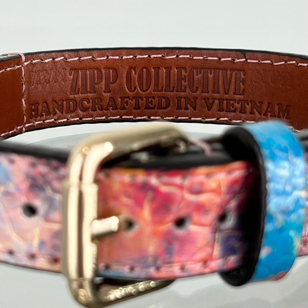 Brown leather lining stamped ZIPP COLLECTIVE — HANDCRAFTED IN VIETNAM, bordered by pale pink hand-stitching.