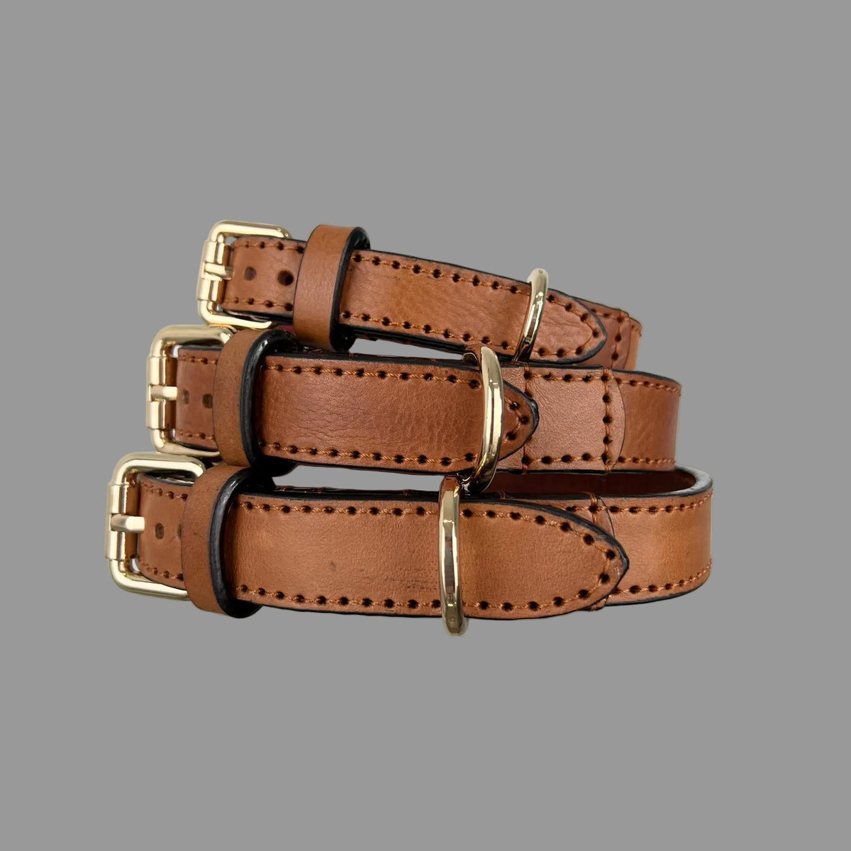 Front view of M, L and XL saddle brown leather dog collars with gold-tone buckles and brown leather keepers.