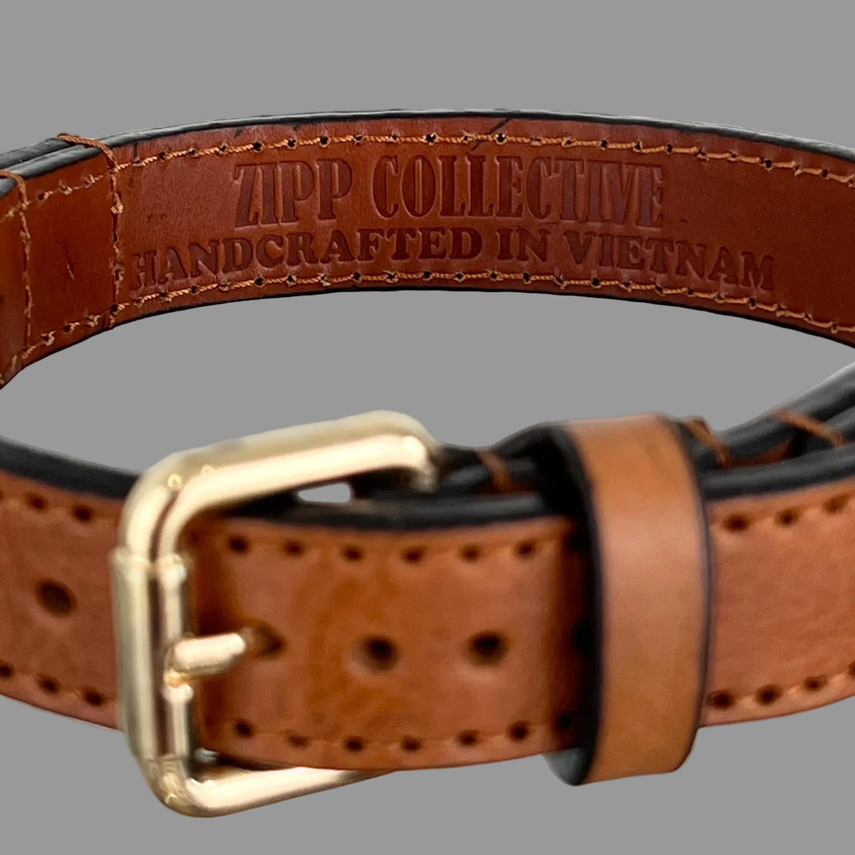ZIPP COLLECTIVE handcrafted in Vietnam stamp inside a saddle brown leather dog collar with brown stitching.