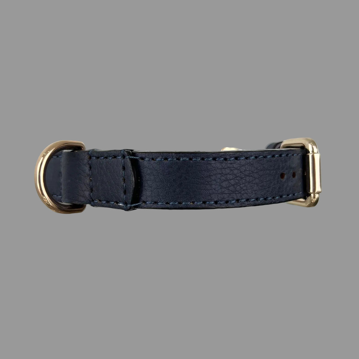 Side view of a navy blue cowhide dog collar showing its fine grain, blue hand stitching and reinforced D-ring attachment.