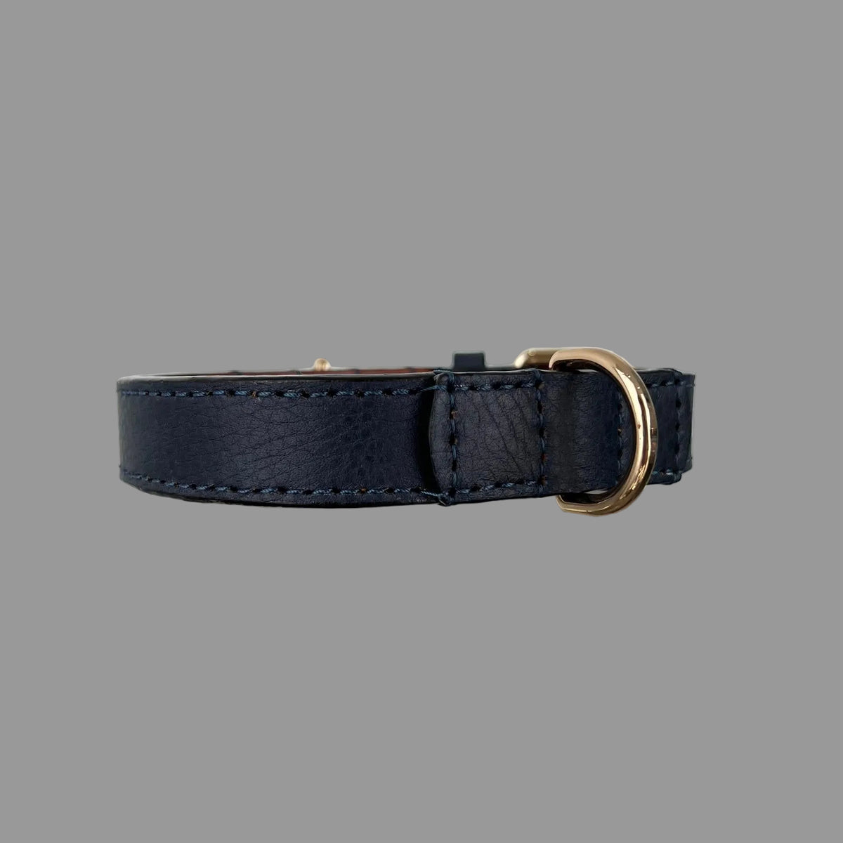 Navy blue dog collar showing pebbled cowhide, tonal blue stitching, brown leather lining and a gold-tone D-ring.