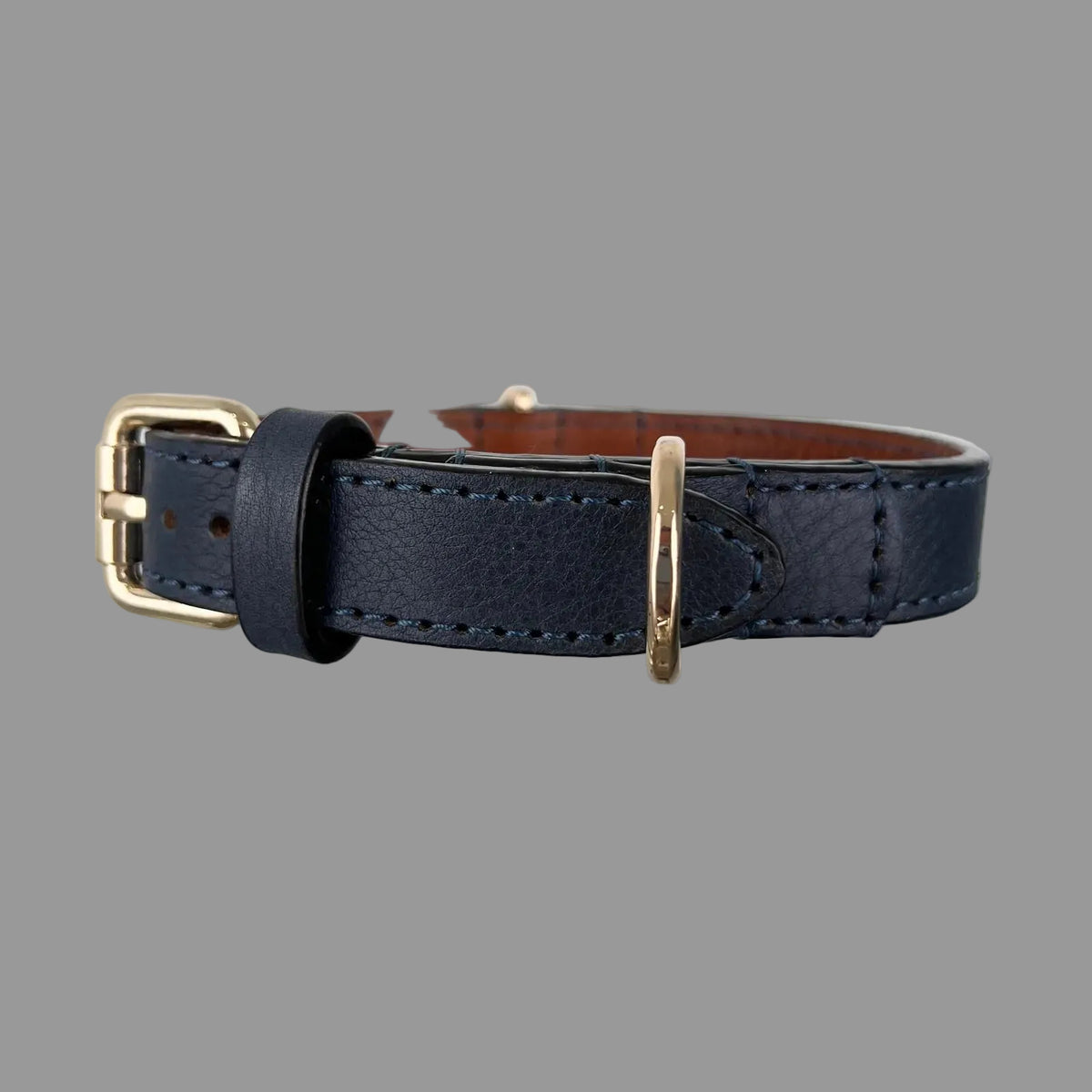 Angled view of a navy blue collar showing its gold-tone buckle, leather keeper, rounded strap end and D-ring.