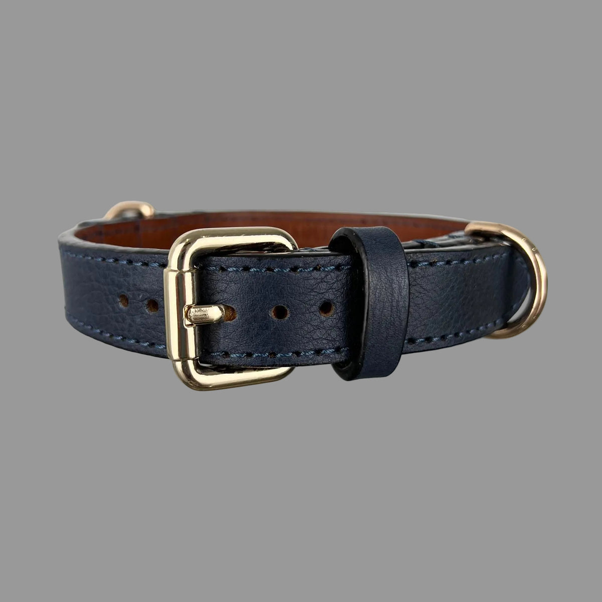 Navy blue dog collar showing pebbled cowhide, tonal blue stitching, brown leather lining and a gold-tone D-ring.