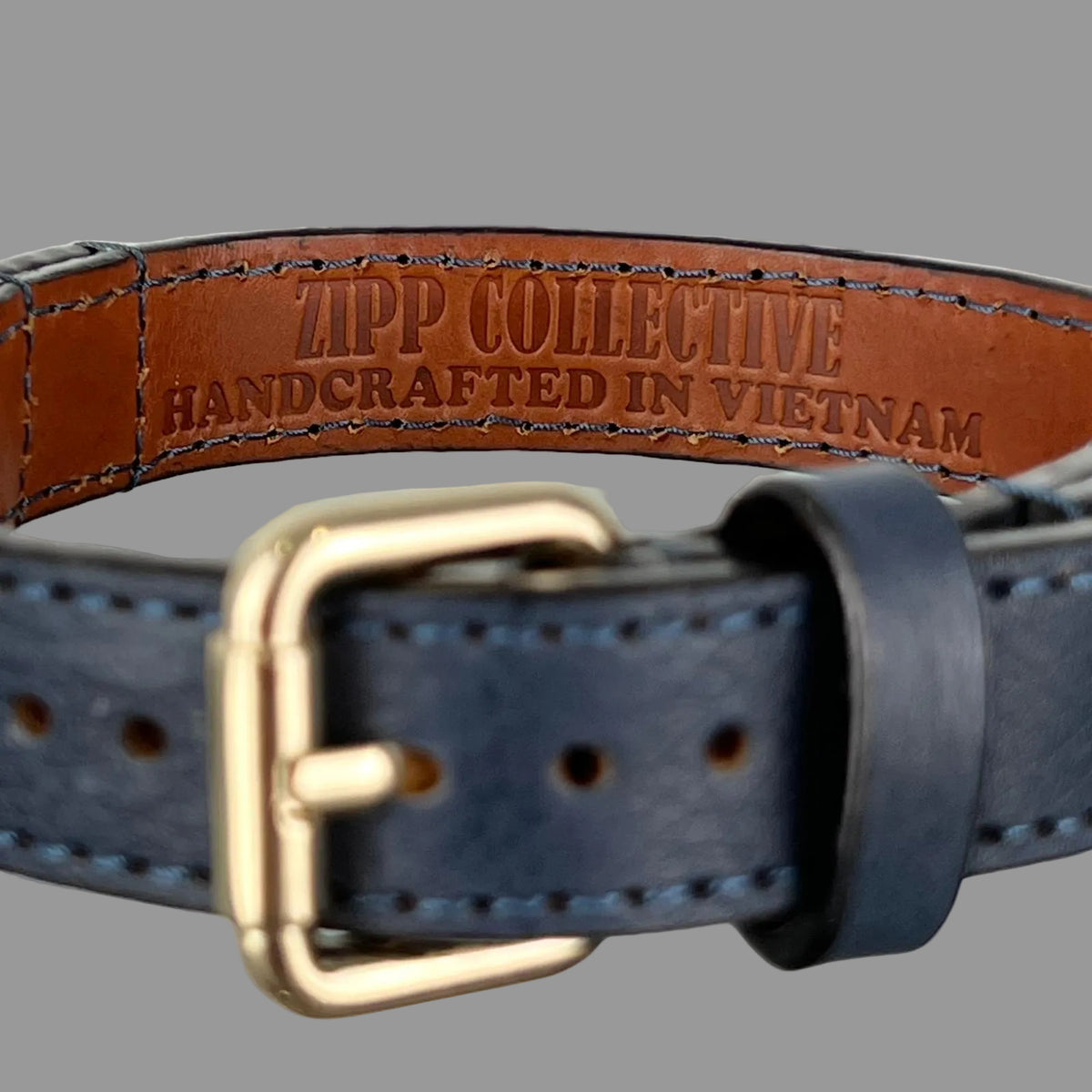 ZIPP COLLECTIVE handcrafted in Vietnam stamp on brown collar lining, bordered by blue hand stitching.