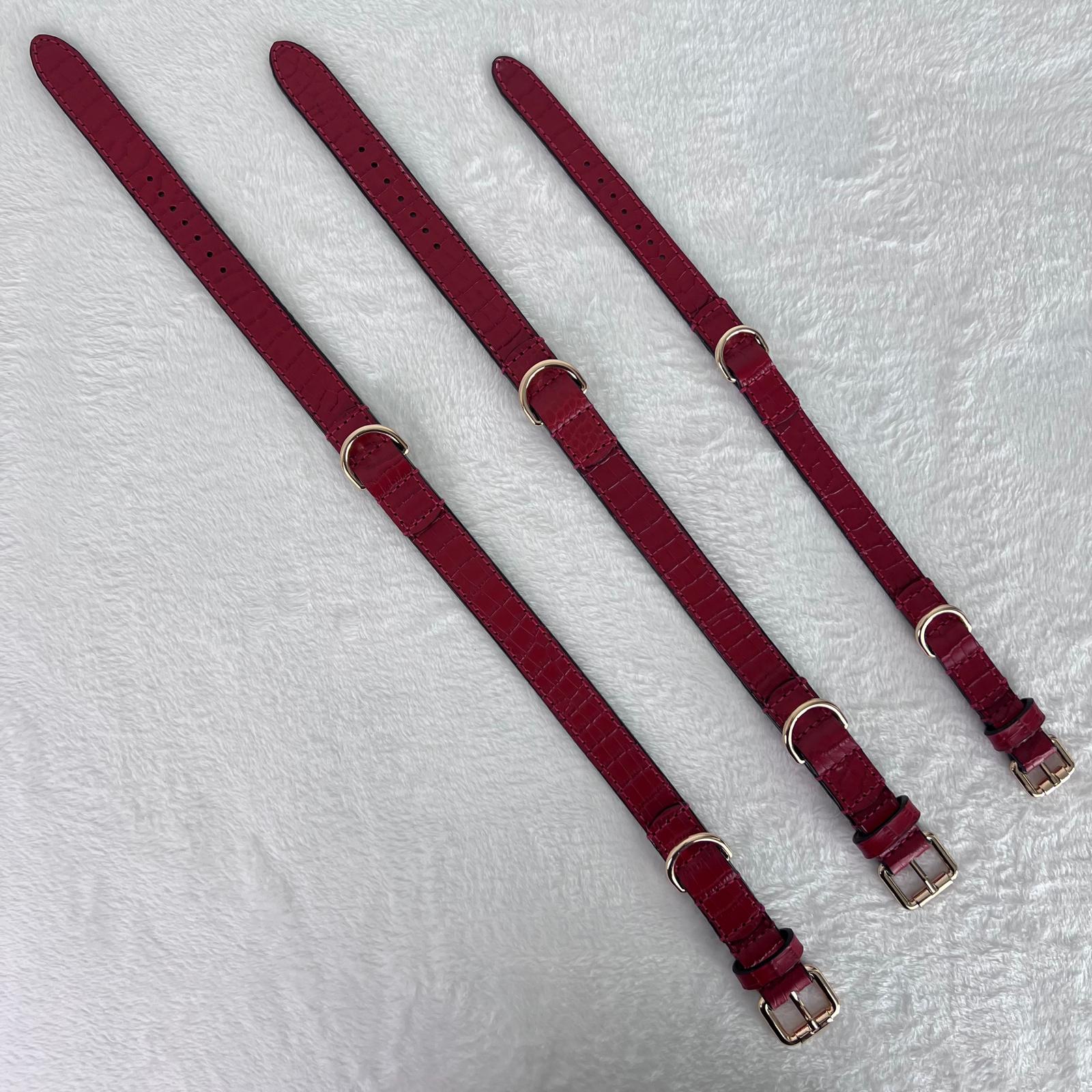 Three ruby red leather dog collars laid flat in sizes M, L and XL