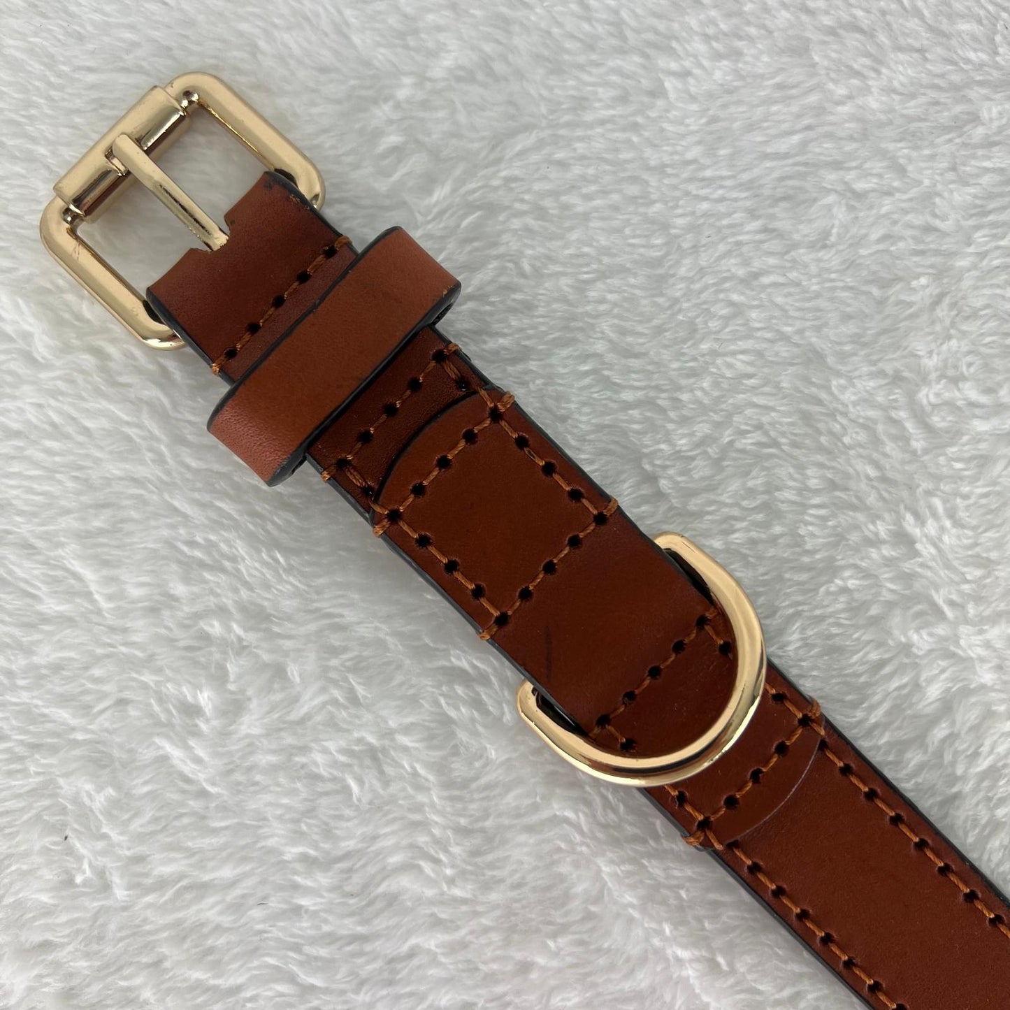 Close-up of hand stitching, gold-tone buckle and reinforced D-ring on a cognac leather dog collar