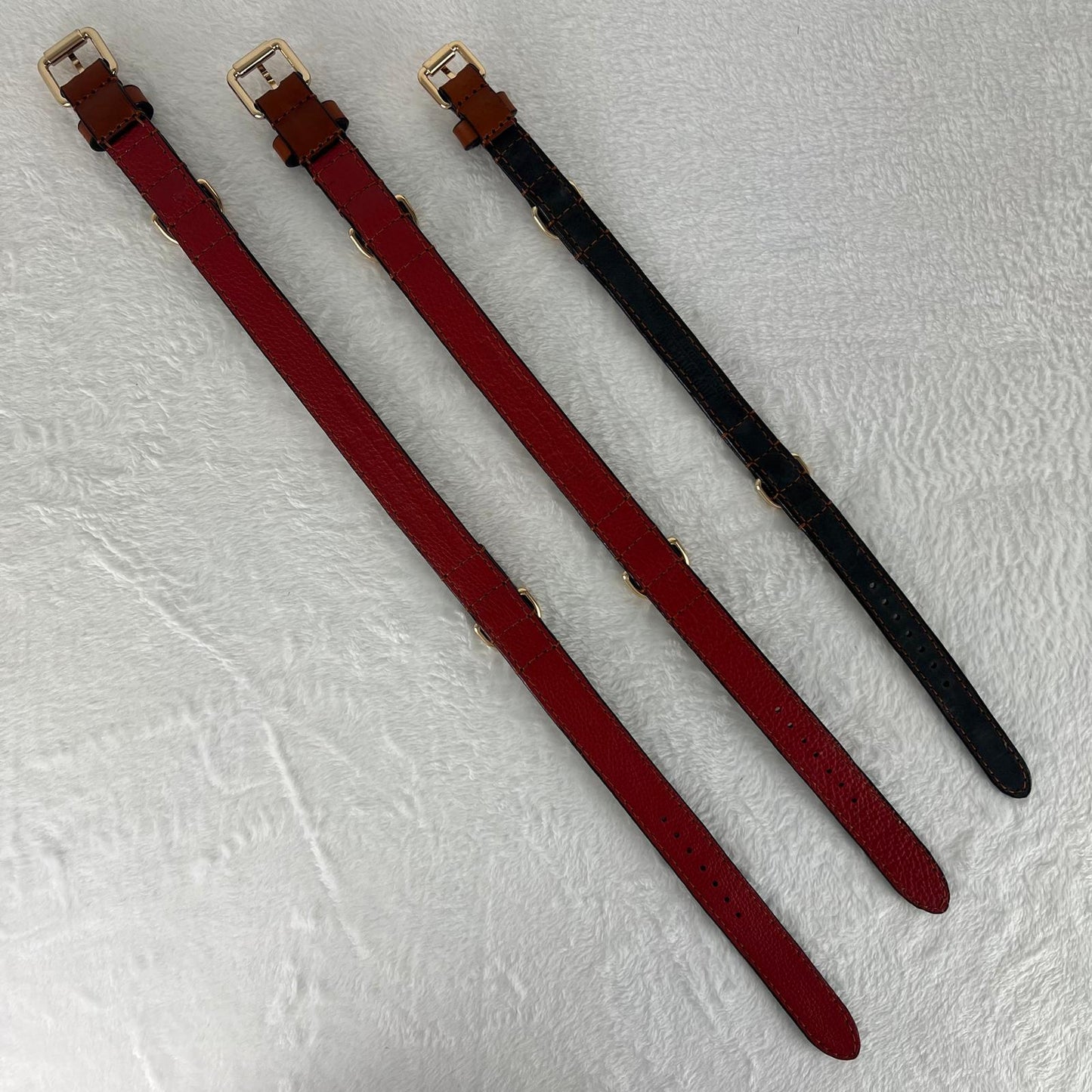 Three cognac brown leather dog collars laid flat showing the different linings in sizes M, L and XL