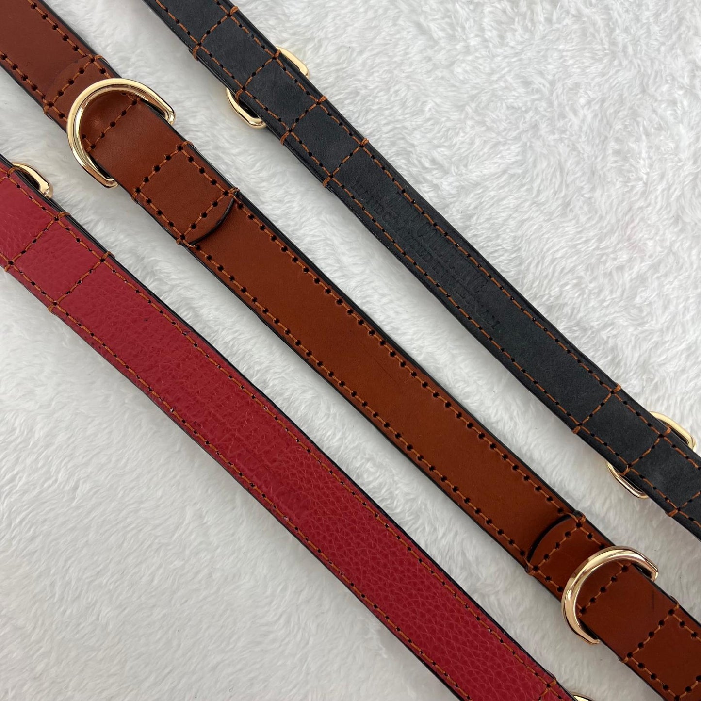 Close-up of cognac brown full-grain leather dog collars showing suede and red pebbled cowhide linings