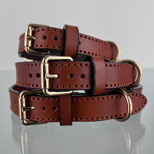 Three handmade cognac brown leather dog collars stacked in sizes M, L and XL