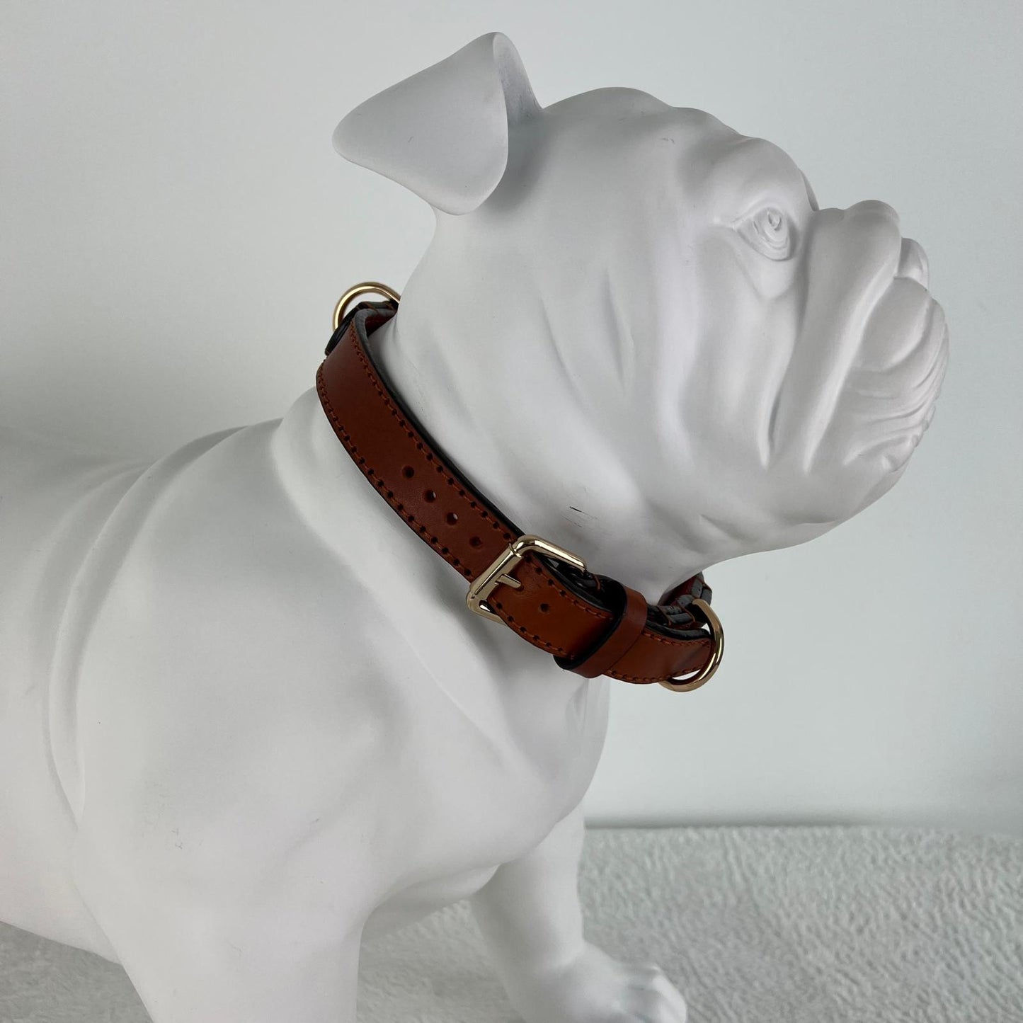 Close-up fit of a cognac brown leather dog collar with gold-tone hardware on a Bulldog mannequin